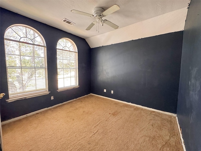 empty room with visible vents, baseboards, ceiling fan, vaulted ceiling, and carpet floors