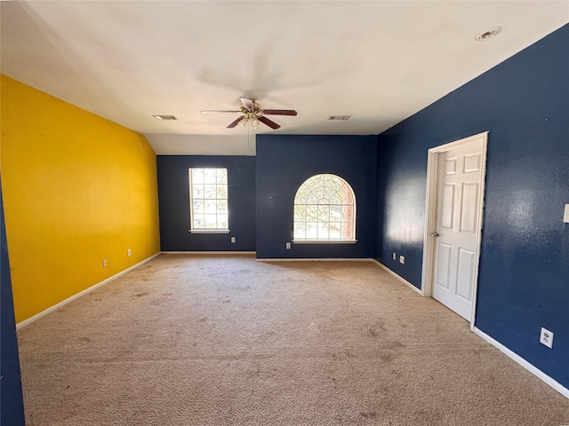 carpeted spare room featuring a ceiling fan, visible vents, and baseboards