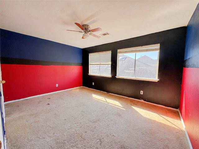 carpeted empty room with visible vents, ceiling fan, and baseboards