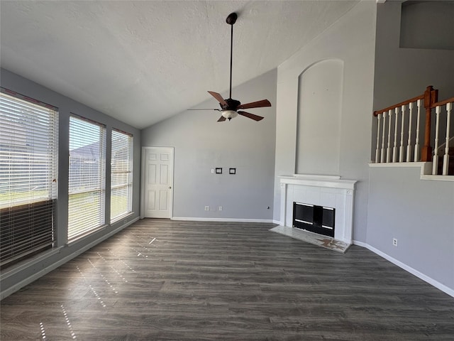 unfurnished living room featuring a textured ceiling, baseboards, dark wood-style flooring, and a tile fireplace