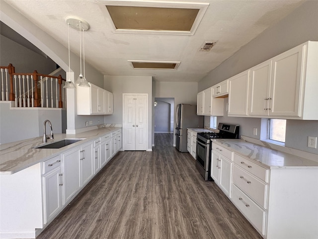 kitchen featuring appliances with stainless steel finishes, white cabinetry, a sink, and a peninsula