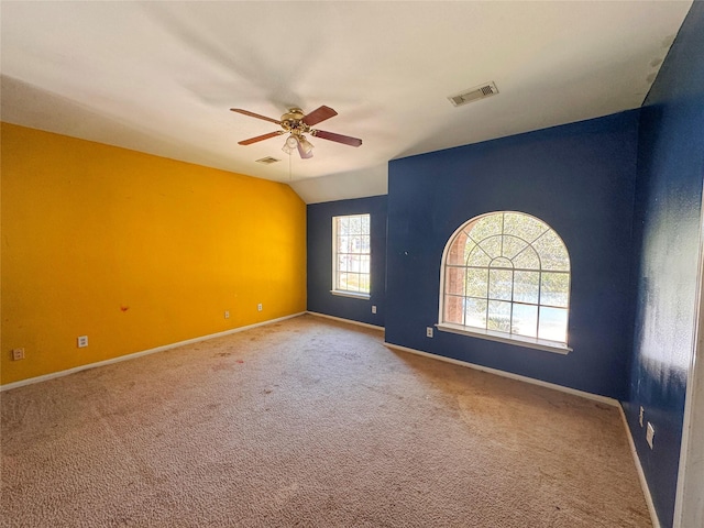 carpeted empty room featuring vaulted ceiling, baseboards, visible vents, and a ceiling fan