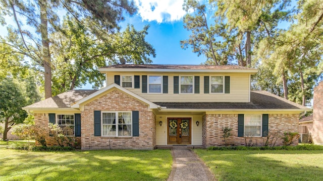 traditional-style house featuring a front lawn, french doors, and brick siding