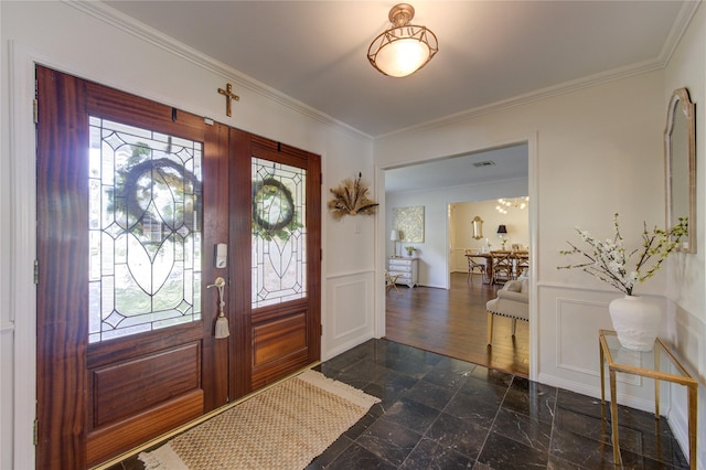 entryway with crown molding, wainscoting, and a decorative wall