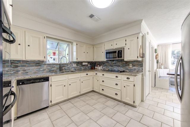 kitchen with light stone counters, stainless steel appliances, tasteful backsplash, visible vents, and a sink