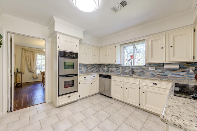 kitchen featuring stainless steel appliances, a sink, visible vents, decorative backsplash, and crown molding