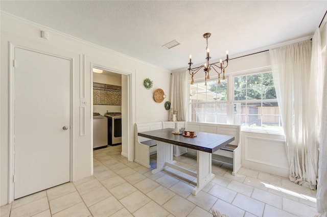 unfurnished dining area with a textured ceiling, washer and dryer, breakfast area, an inviting chandelier, and crown molding