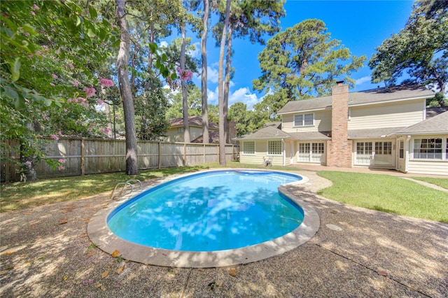 view of swimming pool featuring a fenced in pool, a patio area, a fenced backyard, and a yard