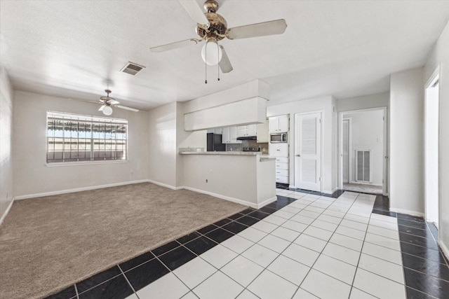 kitchen with tile patterned floors, visible vents, stainless steel microwave, carpet floors, and a peninsula