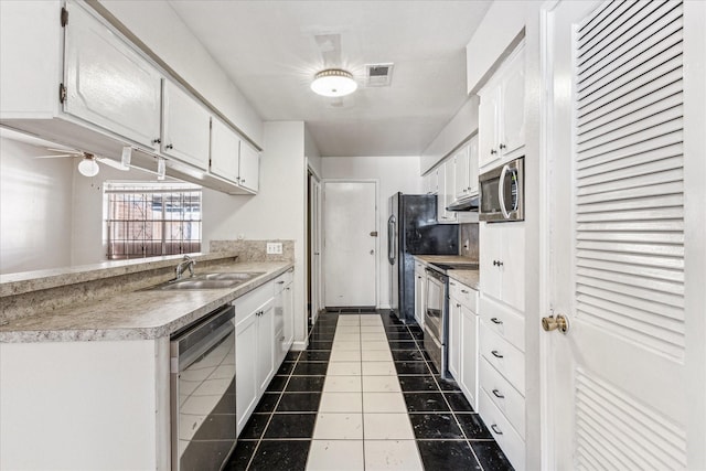 kitchen featuring tile patterned flooring, white cabinets, stainless steel appliances, and a sink