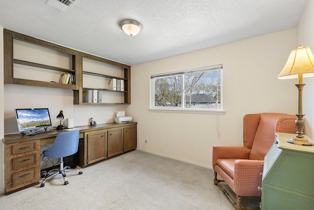 office featuring light carpet, visible vents, a textured ceiling, and built in study area