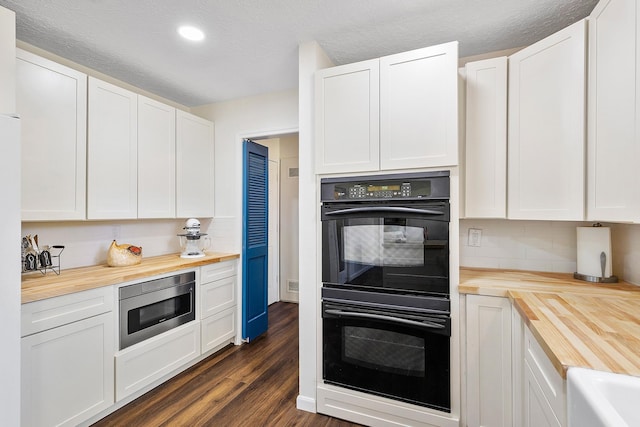 kitchen with stainless steel microwave, dobule oven black, dark wood-type flooring, and butcher block counters