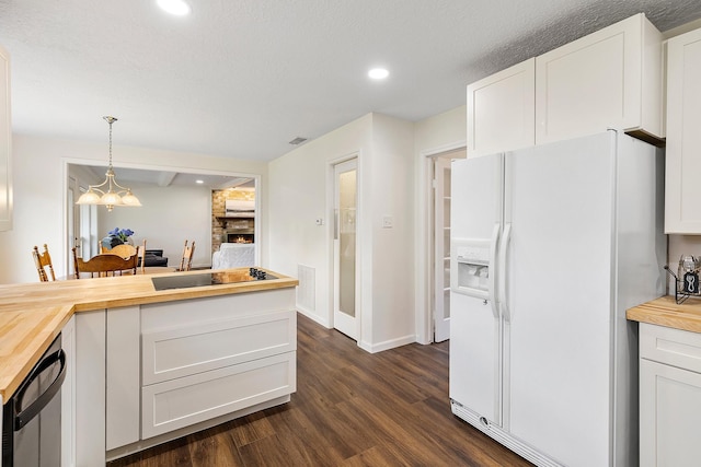 kitchen with visible vents, white refrigerator with ice dispenser, dark wood finished floors, white cabinetry, and wooden counters