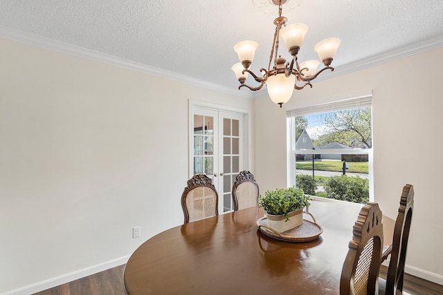 dining room featuring a textured ceiling, crown molding, dark wood-style floors, and a chandelier