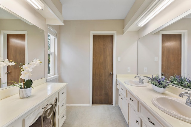 full bath with double vanity, baseboards, and a sink