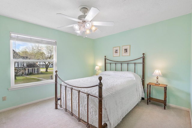 bedroom featuring baseboards, carpet floors, a textured ceiling, and ceiling fan