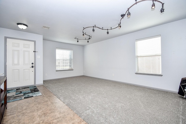 interior space featuring carpet floors, baseboards, visible vents, and track lighting