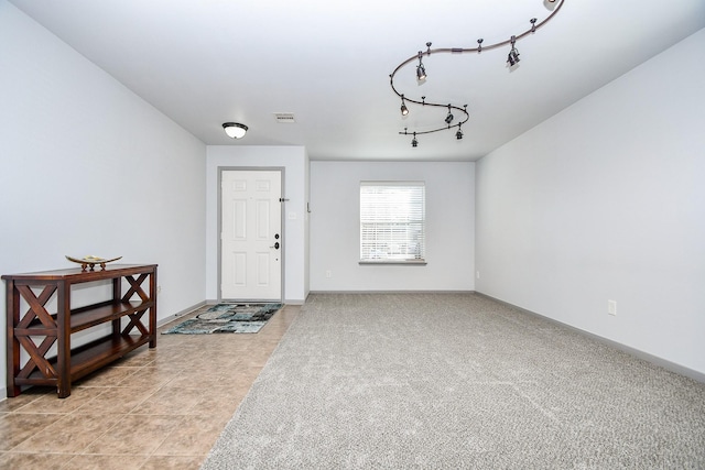 entryway featuring light carpet, light tile patterned floors, baseboards, visible vents, and rail lighting