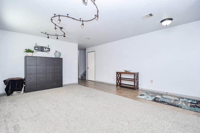 interior space with track lighting, carpet, visible vents, and baseboards