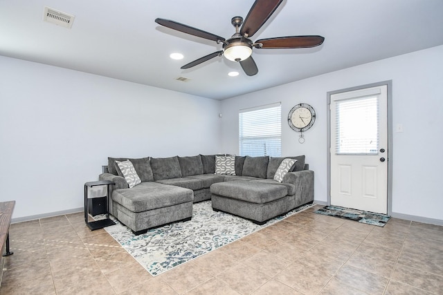 tiled living room featuring baseboards, visible vents, and a ceiling fan