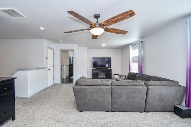 living room with a ceiling fan, light colored carpet, visible vents, and baseboards