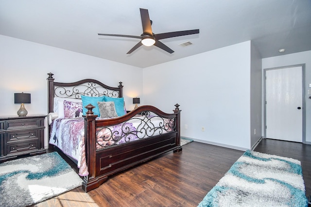 bedroom with a ceiling fan, visible vents, baseboards, and wood finished floors