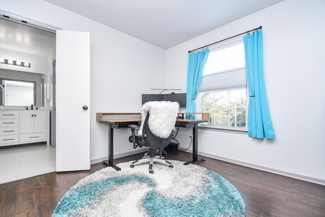 home office with baseboards, a sink, and wood finished floors