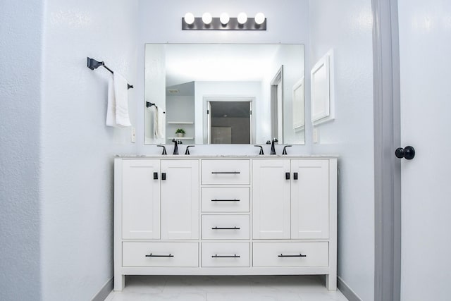 bathroom featuring a sink, baseboards, and double vanity