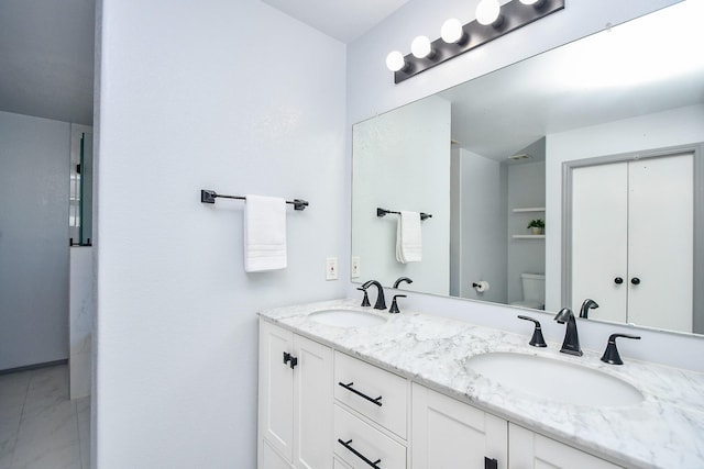 full bathroom with toilet, double vanity, and a sink