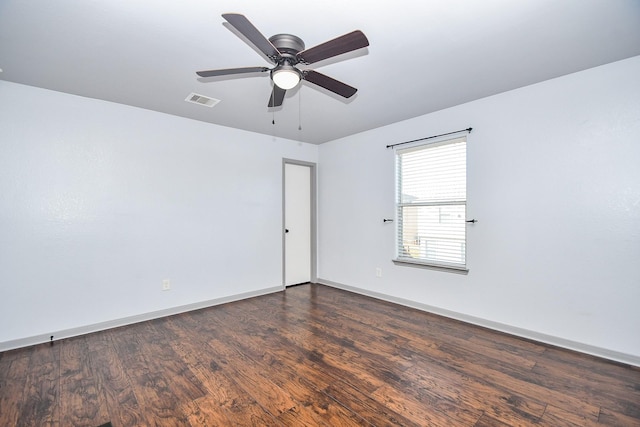 empty room featuring visible vents, dark wood finished floors, baseboards, and ceiling fan