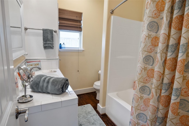 full bathroom with baseboards, toilet, shower / tub combo with curtain, wood finished floors, and a sink