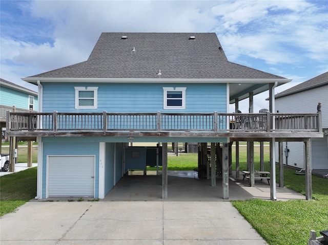 rear view of house with a carport, a yard, roof with shingles, and driveway