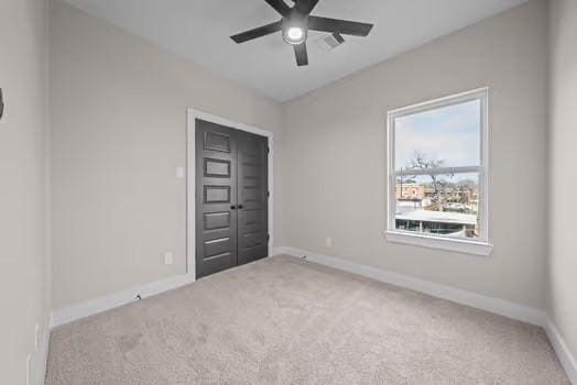 empty room with carpet, baseboards, and a ceiling fan