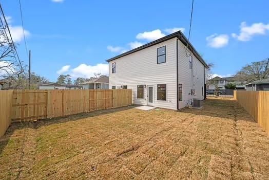 rear view of house featuring central AC, a lawn, and a fenced backyard