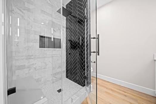 bathroom featuring a stall shower, baseboards, and wood finished floors