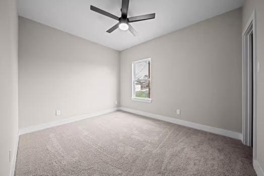 carpeted spare room featuring a ceiling fan and baseboards