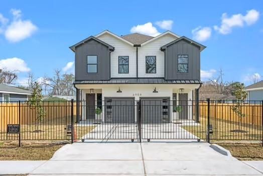 view of front of home with a fenced front yard, a gate, driveway, and board and batten siding