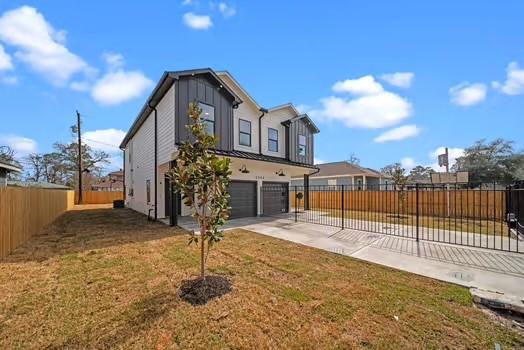 view of front of house featuring an attached garage, fence, a front lawn, and concrete driveway