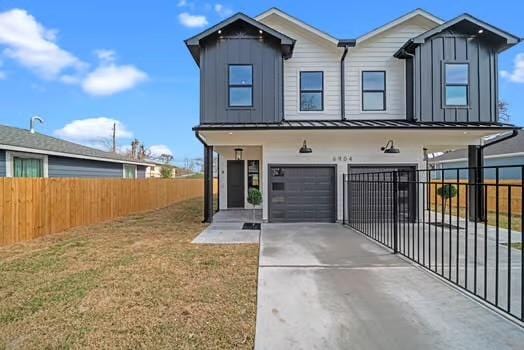 view of front facade featuring concrete driveway, board and batten siding, an attached garage, and fence