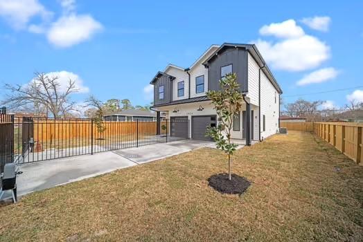 exterior space featuring concrete driveway, a yard, an attached garage, and fence private yard