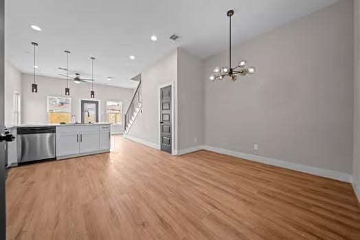 kitchen with baseboards, open floor plan, hanging light fixtures, light wood-type flooring, and dishwasher