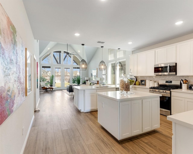 kitchen featuring light wood-type flooring, visible vents, stainless steel appliances, light countertops, and decorative backsplash