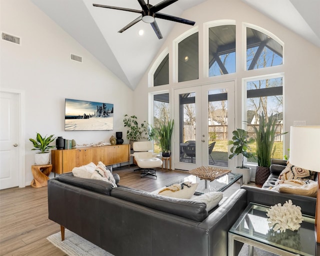 living area with visible vents, high vaulted ceiling, wood finished floors, and a ceiling fan