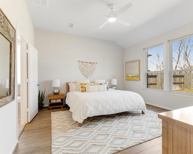 bedroom with visible vents, baseboards, lofted ceiling, light wood-style floors, and a ceiling fan