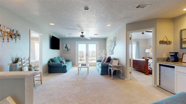 living area with light carpet, french doors, a textured ceiling, and visible vents