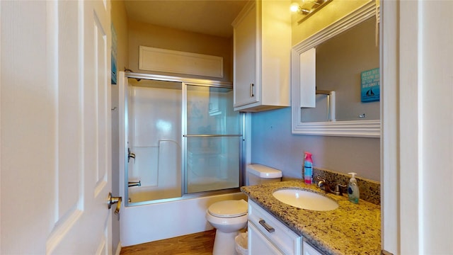 bathroom featuring enclosed tub / shower combo, vanity, toilet, and wood finished floors