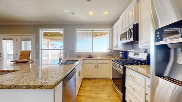 kitchen featuring crown molding, appliances with stainless steel finishes, a sink, and white cabinets