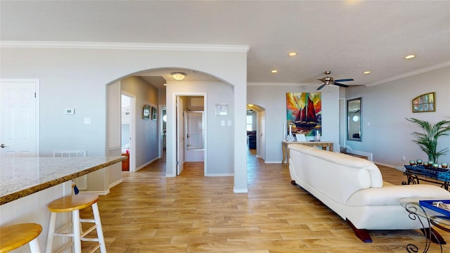 living area featuring arched walkways, light wood-style flooring, baseboards, and recessed lighting