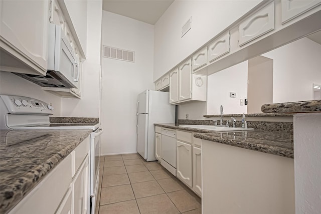 kitchen with light tile patterned flooring, white appliances, a sink, visible vents, and white cabinetry