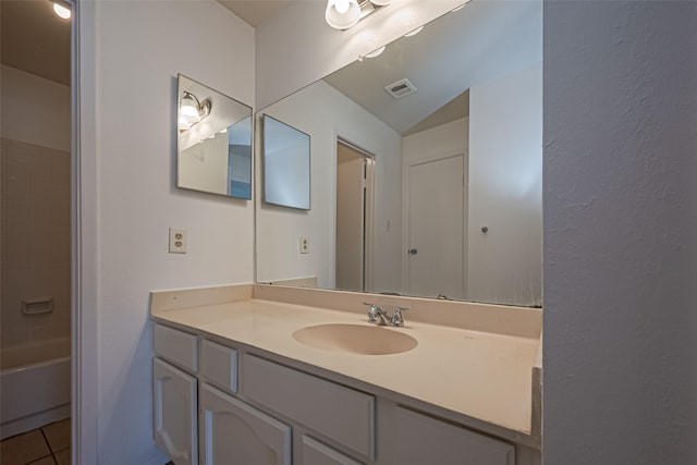 bathroom featuring vanity, visible vents, vaulted ceiling, and tile patterned floors